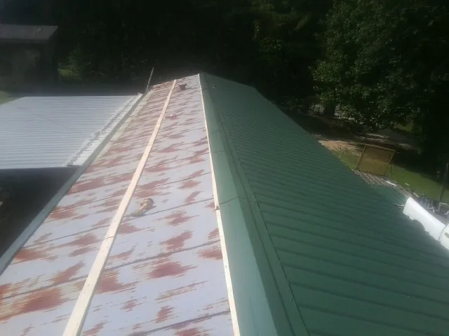 Old rusted panels beside newly installed green metal roofing — Wind Damage Roof Repair by Roofing Brothers in Point Pleasant
