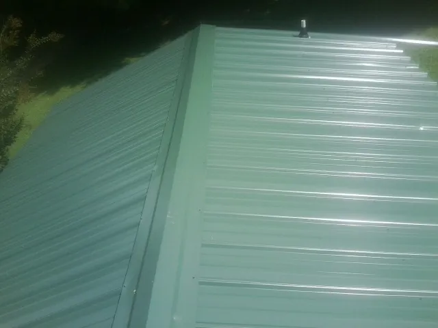 New green metal panels meeting at the ridge of a roof — Flat Roof Repair work by our crew in Point Pleasant