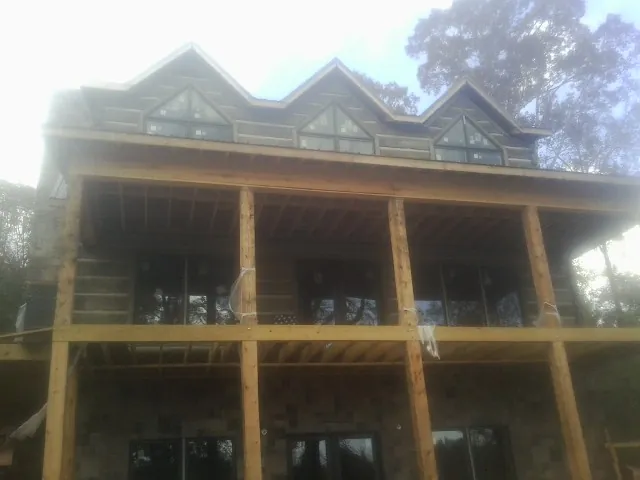 Dormers and porch framing on a large log home under construction — Roof Coating work by our crew in Point Pleasant