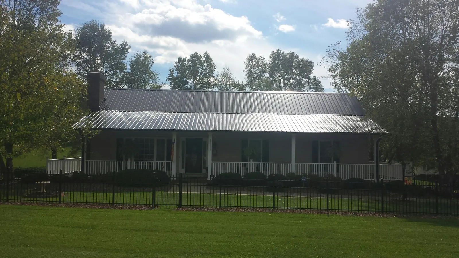 Gray metal roof on a brick ranch with a full width front porch — Gutter Guard Installation work by our crew in Point Pleasant