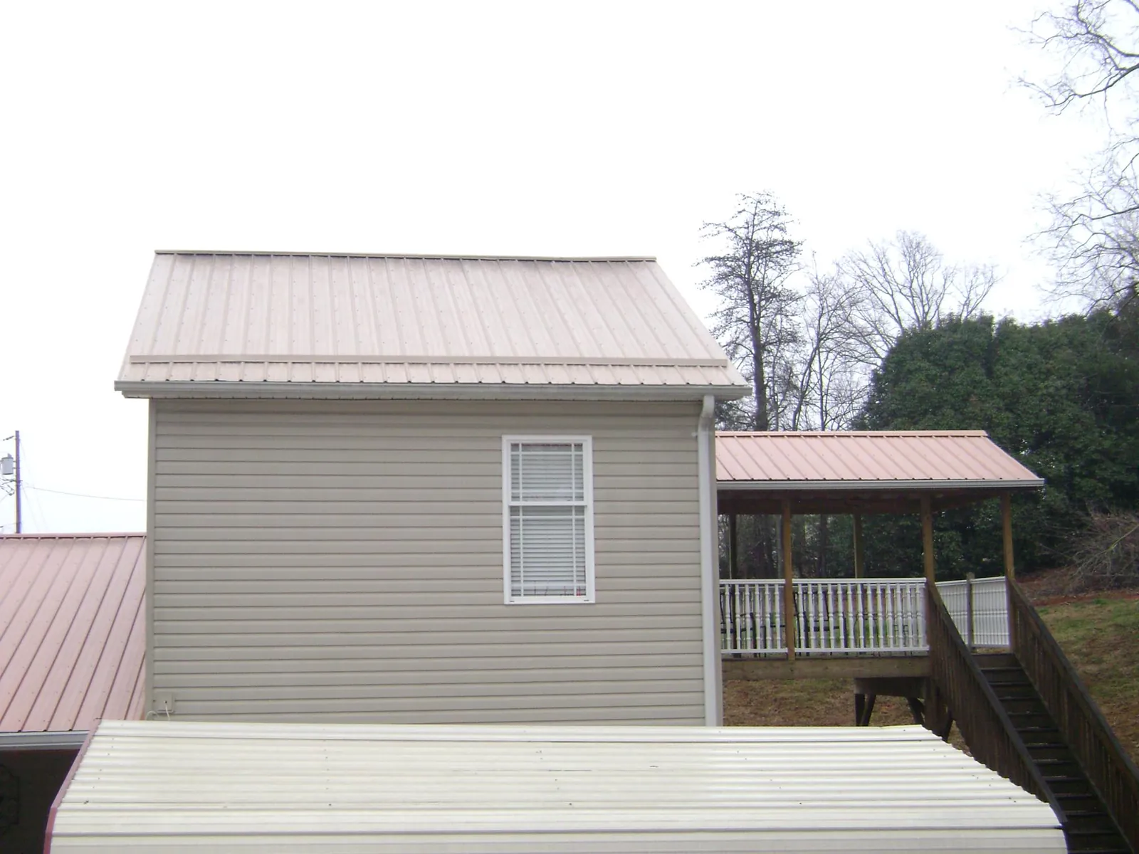 Tan metal roofs on a two story addition and attached porch, from a Roof Replacement job in Point Pleasant