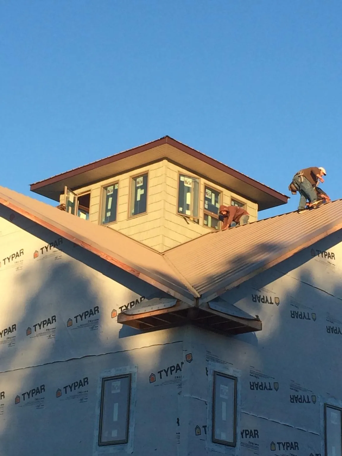 Roofers working around a rooftop cupola on a new metal roof at sunset — Roof Waterproofing in Point Pleasant by Roofing Brothers